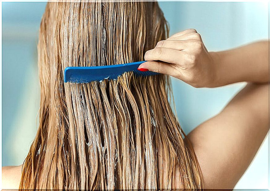 Woman applying a product to her hair with a comb: healthy and silky hair