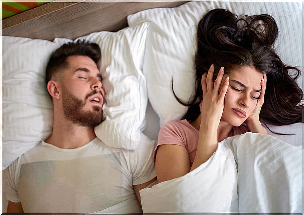 Woman covering her ears in bed before the snoring of the couple.