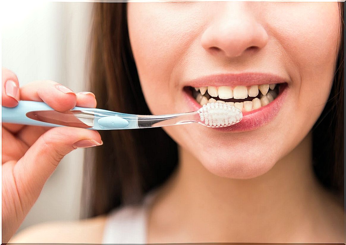 Woman brushes her teeth due to xerostomia.